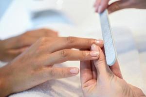 femme dans un salon de manucure recevant une manucure avec lime à ongles photo