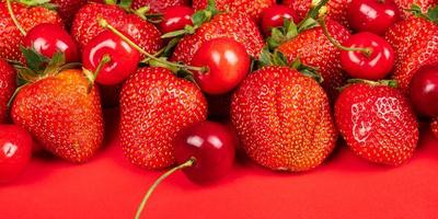 cerise douce et fraises sur fond rouge close up photo