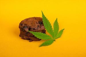 biscuits au cannabis et marijuana à feuilles vertes sur fond jaune, traitement de la marijuana médicale à utiliser dans les aliments photo