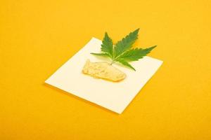 haute teneur en thc, morceaux de cire de cannabis jaune doré et feuille verte, concentré de marijuana photo