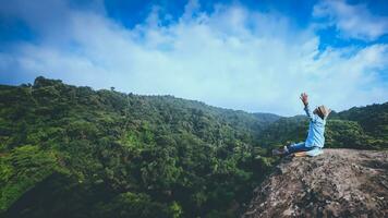 asiatique homme Voyage se détendre dans le vacances. des places se détendre lis livres sur rocheux falaises. sur le montagne été. dans Thaïlande photo