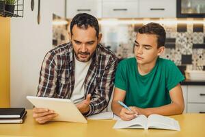 père est portion le sien fils avec apprentissage. elles ou ils sont Faire devoirs ensemble. photo