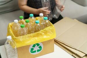 Accueil recycler éco vert zéro concept femme lancement vide Plastique bouteille dans recyclage poubelle avec Jaune des ordures Sacs à maison. photo