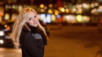 belle femme blonde dans les lumières de la voiture dans la ville de nuit. photo