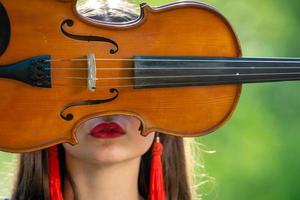 portrait d'une jeune femme positive. une partie du visage est recouverte par le manche du violon - image photo