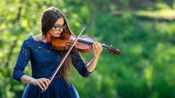 jeune femme jouant du violon au parc. faible profondeur de champ - image