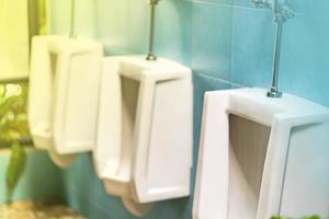 rangée d'urinoirs blancs dans les toilettes pour hommes photo