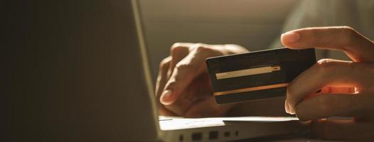 main tenant une carte de crédit et utilisant un ordinateur portable pour faire des achats en ligne photo