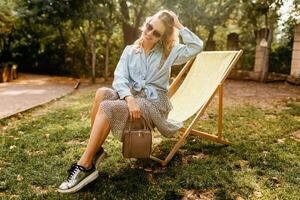 élégant blond femme séance dans ville parc été mode photo