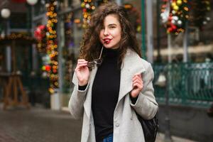 Jeune magnifique femme en marchant dans le ville rue dans gris manteau photo