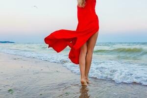 magnifique gratuit femme dans rouge robe dans vent sur mer plage photo