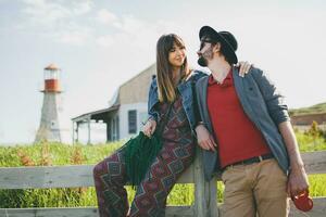 en riant Jeune branché couple indie style dans l'amour en marchant dans campagne photo