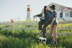 élégant branché couple dans l'amour en marchant avec chien dans campagne photo