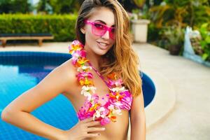 sexy femme sur été vacances ayant amusement à bassin portant bikini et rose des lunettes de soleil photo