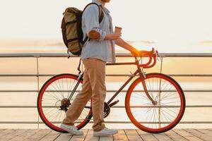Beau barbu homme en voyageant avec vélo dans Matin lever du soleil par le mer photo