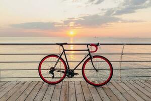 branché vélo dans Matin lever du soleil par le mer photo