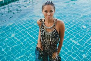 Jeune asiatique sexy magnifique femme dans tropical robe, zèbre imprimer, posant dans bassin photo