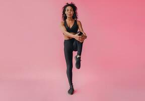 attrayant noir africain américain femme dans noir leggins aptitude tenue sur rose Contexte photo