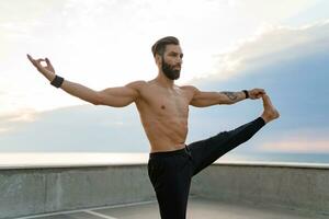 attrayant beau homme avec athlétique fort corps Faire Matin yoga asana en plein air photo