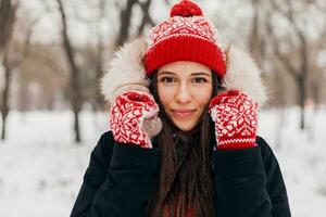 proche en haut portrait de Jeune jolie Candide souriant content femme dans rouge Mitaines et tricoté chapeau portant fourrure manteau en marchant en jouant dans parc dans neige, chaud vêtements, ayant amusement photo