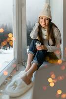 femme séance à fenêtre dans hiver Noël maison photo