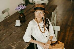 magnifique femme séance dans café sur vacances habillé dans blanc été mode robe photo