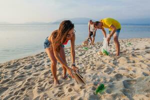 Jeune gens copains cueillette en haut poubelle et des ordures sur tropical plage photo