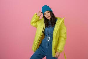 attrayant actif femme modèle posant sur rose Contexte dans coloré hiver vers le bas veste de brillant rjaune couleur, chaud manteau mode tendance photo