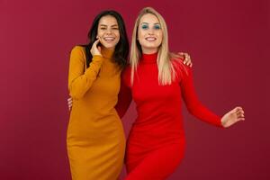 content souriant jolie élégant femmes dans Jaune et rouge l'automne hiver mode tricoté robe posant isolé sur rouge studio Contexte photo