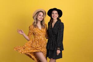 magnifique femmes copains ensemble isolé sur Jaune Contexte dans noir et Jaune robe et chapeau photo