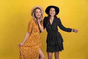 magnifique femmes copains ensemble isolé sur Jaune Contexte dans noir et Jaune robe et chapeau photo