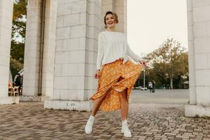 Jeune jolie content souriant femme dans Jaune imprimé robe et tricoté blanc chandail photo