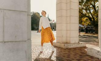 Jeune jolie content souriant femme dans Jaune imprimé robe et tricoté blanc chandail photo