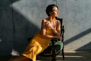 attrayant femme dans Jaune été robe dans intérieur pièce béton mur Contexte photo