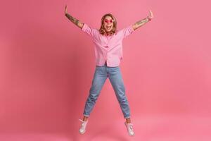 blond jolie femme dans rose chemise et jeans souriant sauter photo