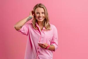 blond jolie femme dans rose chemise souriant en portant en portant en utilisant téléphone intelligent photo