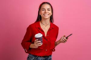 hispanique magnifique femme dans rouge chemise souriant en portant téléphone intelligent photo