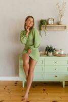 Jeune élégant souriant femme dans vert été robe dans moderne intérieur appartement Accueil photo