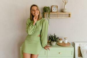 Jeune élégant souriant femme dans vert été robe dans moderne intérieur appartement Accueil photo