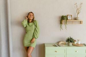 Jeune élégant souriant femme dans vert été robe dans moderne intérieur appartement Accueil photo