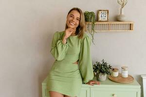 Jeune élégant souriant femme dans vert été robe dans moderne intérieur appartement Accueil photo