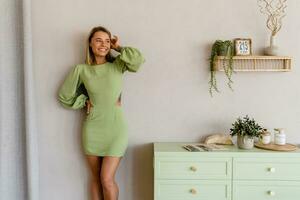 Jeune élégant souriant femme dans vert été robe dans moderne intérieur appartement Accueil photo