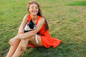 Jeune content souriant femme dans Orange robe ayant amusement en jouant avec chien dans parc photo