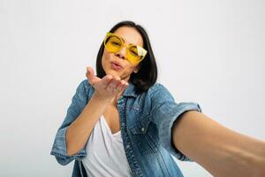 attrayant femme habillé jeans et denim chemise portant Jaune des lunettes de soleil photo