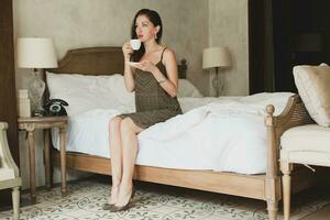 Jeune magnifique femme séance sur lit dans Hôtel pièce photo