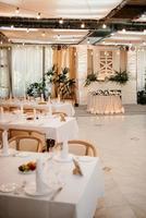 le présidium des jeunes mariés dans la salle de banquet du restaurant est décoré de bougies et de plantes vertes photo