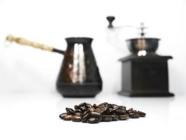 gros plan sur des grains de café et un moulin à café en bois avec un cezva en arrière-plan photo