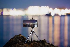 à l'aide d'un smartphone sur un trépied avec une longue exposition de la mer la nuit photo