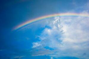 magnifique multicolore arc en ciel après pluie sur le bleu ciel et blanc des nuages. photo