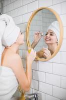 jeune femme en serviette blanche applique de l'huile hydratante sur la peau du visage. photo